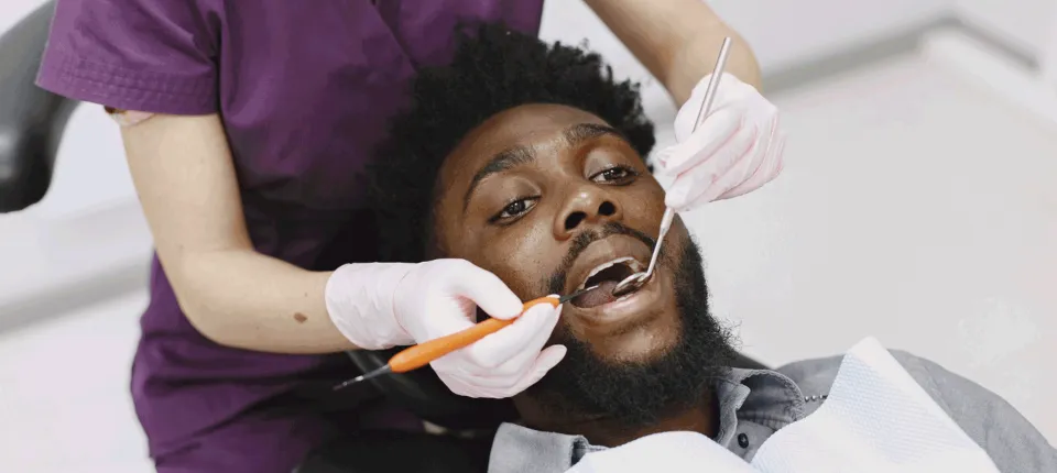 black man at the dentist getting teeth examination