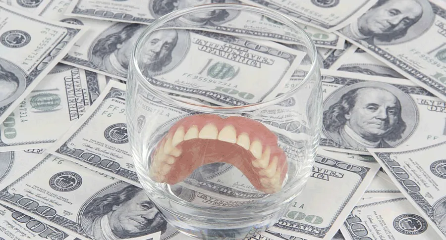 glass with dentures ontop of money