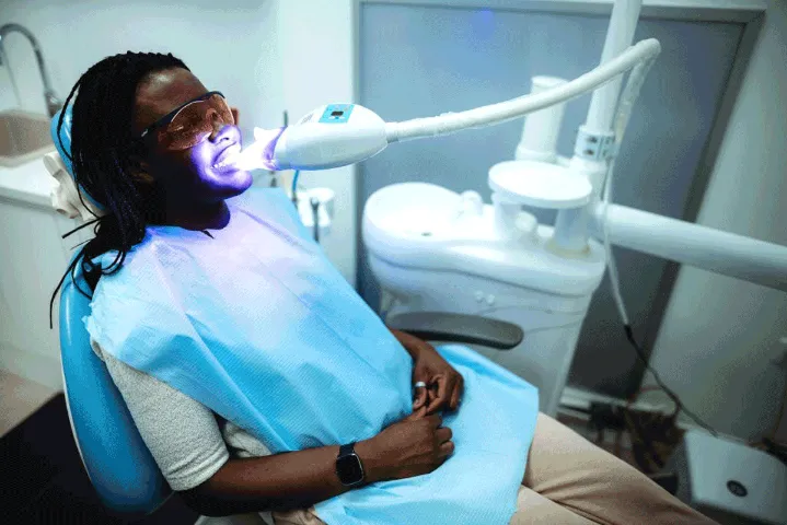 black woman at the dentist whitening her teeth