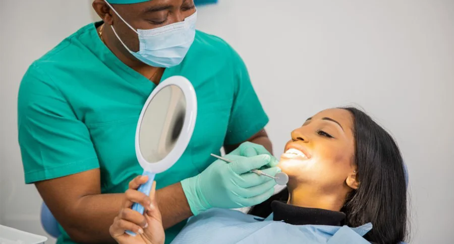 A woman holding a mirror during dentist checkup