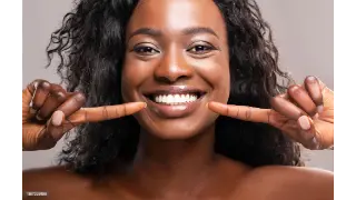 Black woman smiling point at her teeth